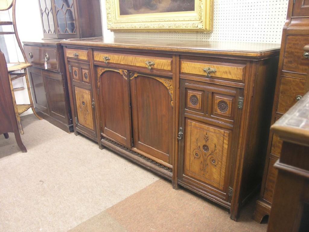 Appraisal: An Arts and Crafts walnut and mahogany sideboard three drawers