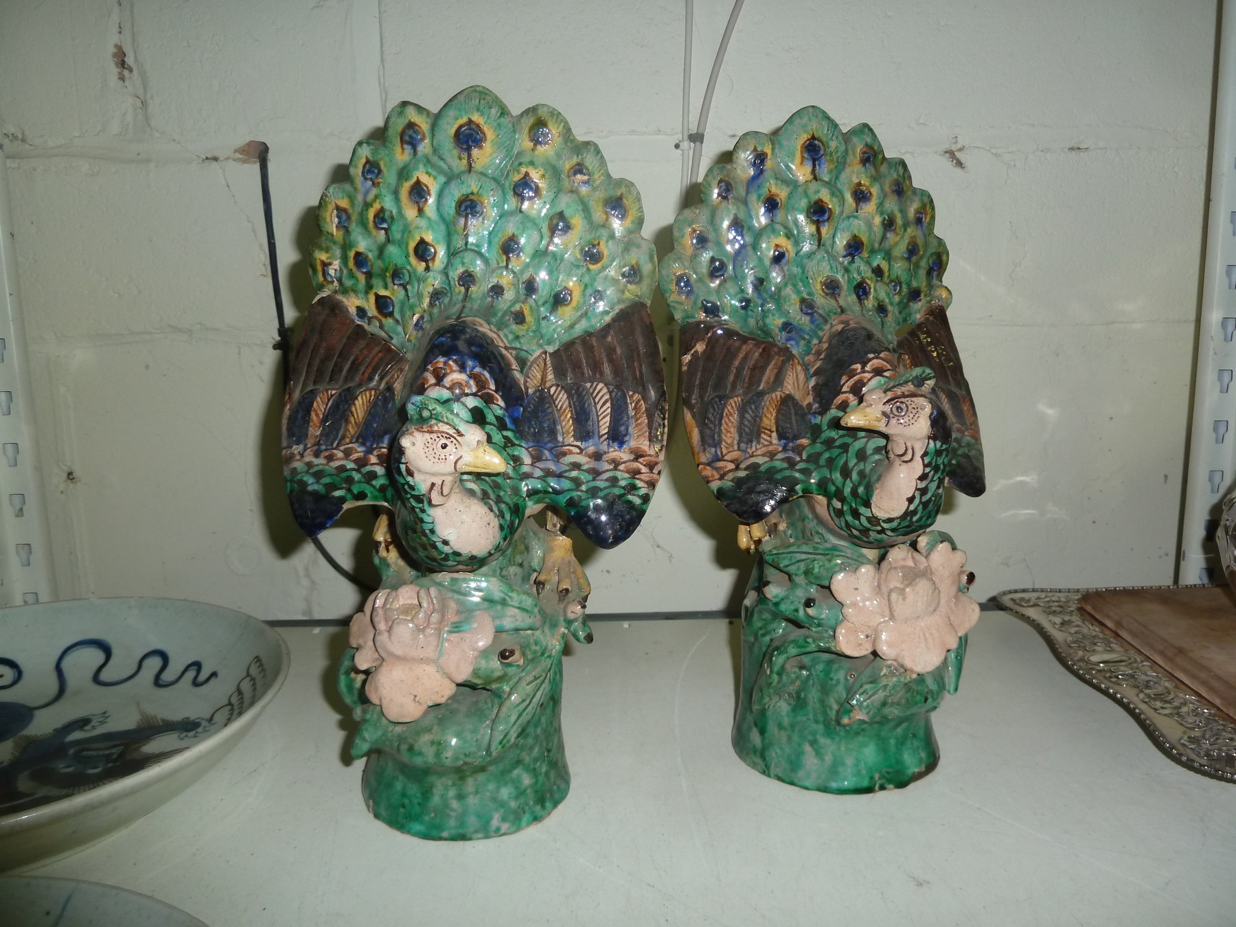 Appraisal: A pair of Oriental pottery peacocks perched on flowering stumps