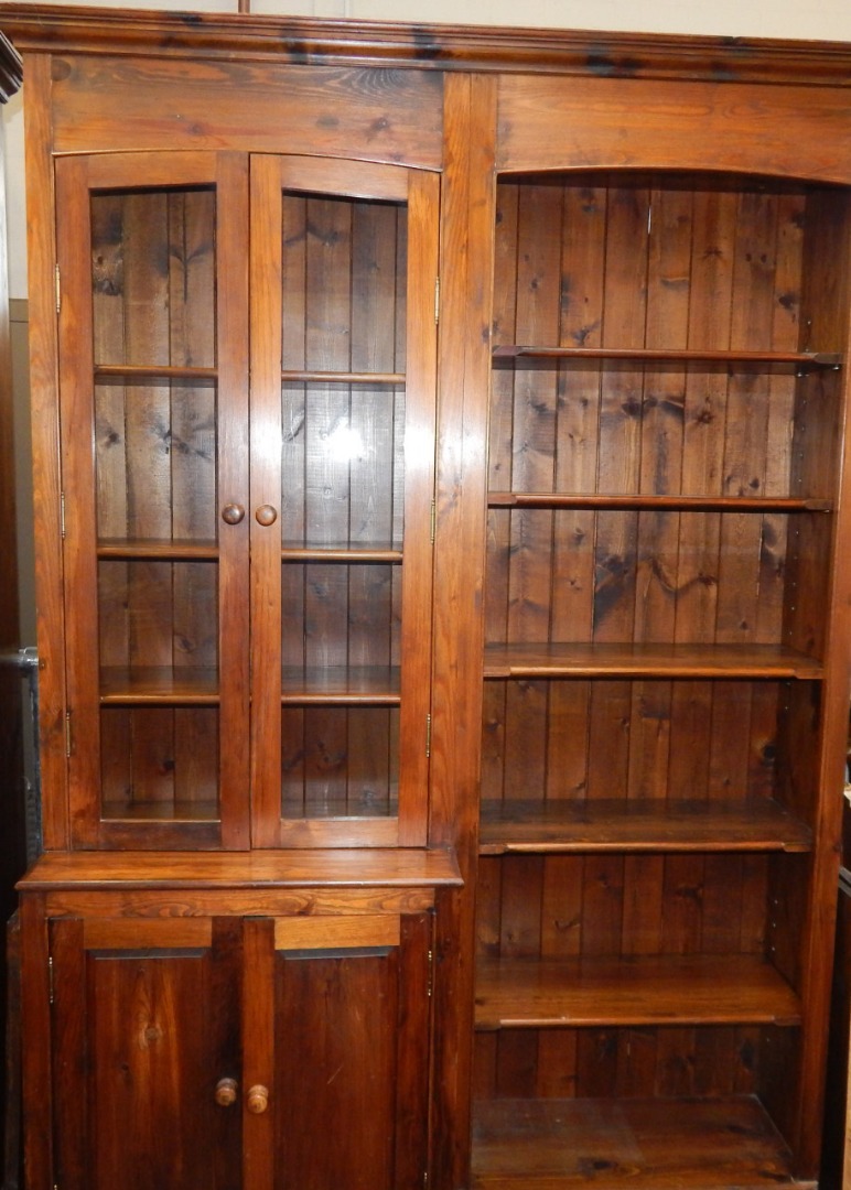 Appraisal: A stained pine cupboard bookcase the out swept pediment over