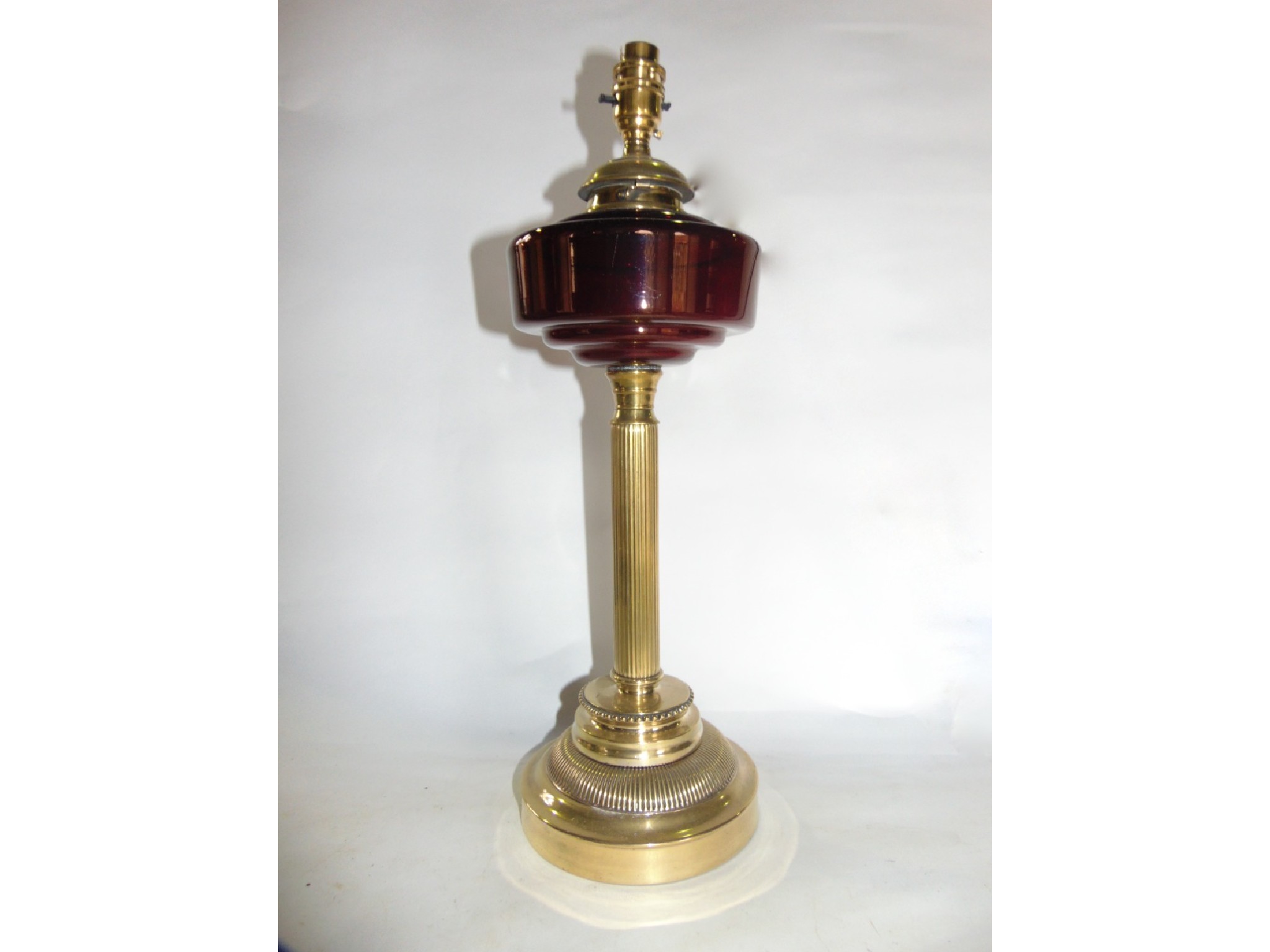 Appraisal: An electrified brass oil lamp raised on a fluted column