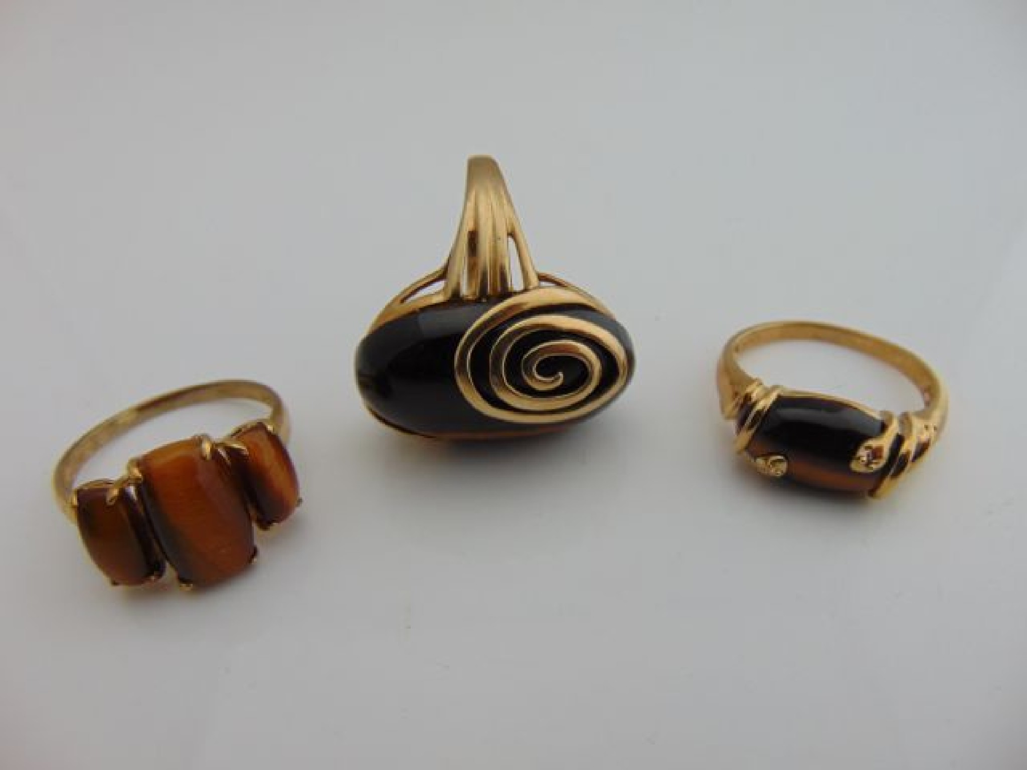 Appraisal: A collection of three tiger's eye rings each in ct