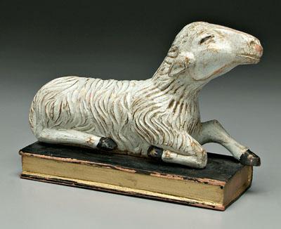 Appraisal: Carved and painted sheep recumbent sheep resting on book carved