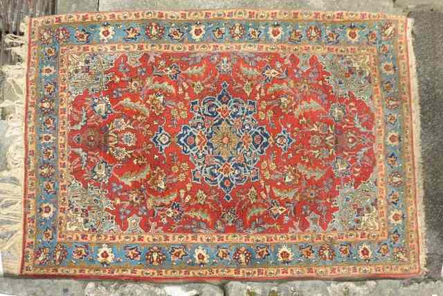 Appraisal: A PERSIAN RED GROUND KASHAN RUG with blue central medallion