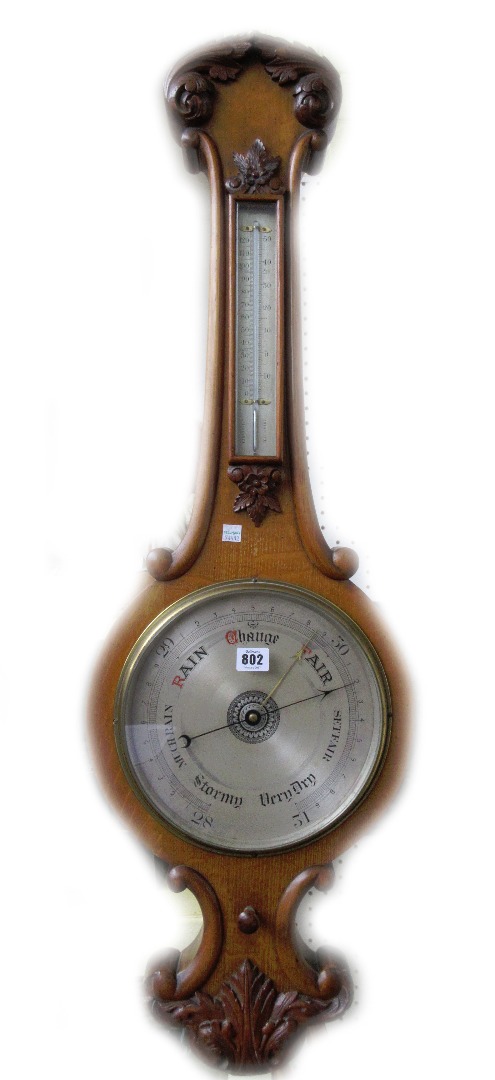 Appraisal: A Victorian oak cased wheel barometer with applied thermometer over