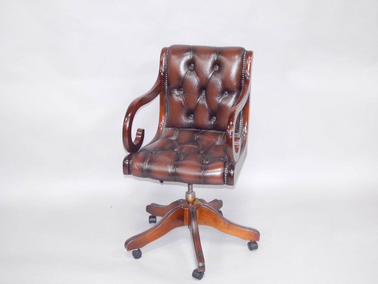 Appraisal: An oak and button back brown leather captain's chair raised