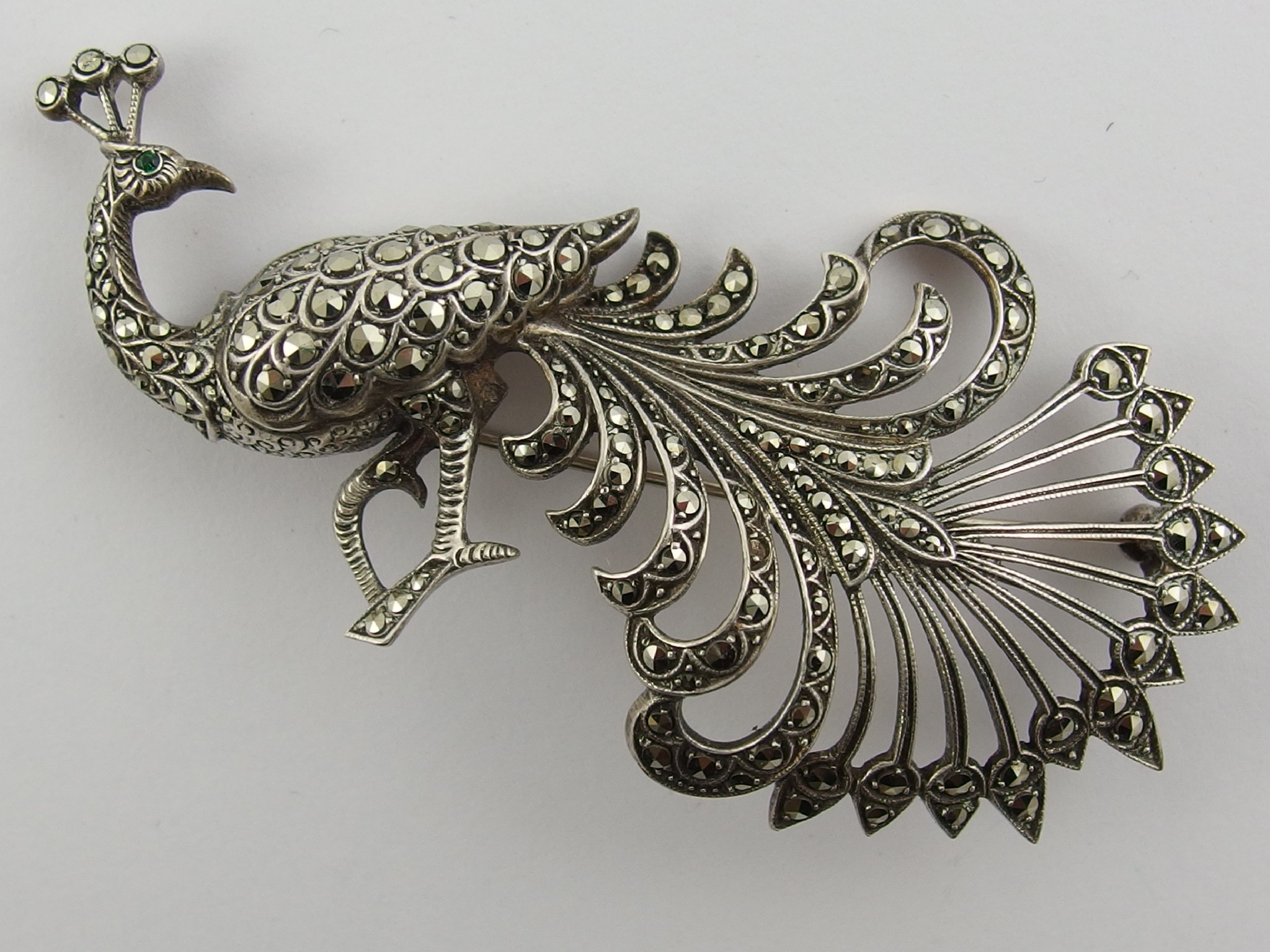 Appraisal: A silver marcasite set peacock brooch with green gem set