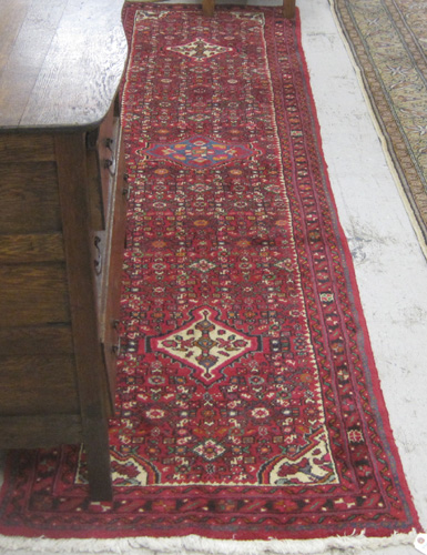 Appraisal: PERSIAN RUNNER hand knotted in a three medallion and Heratif