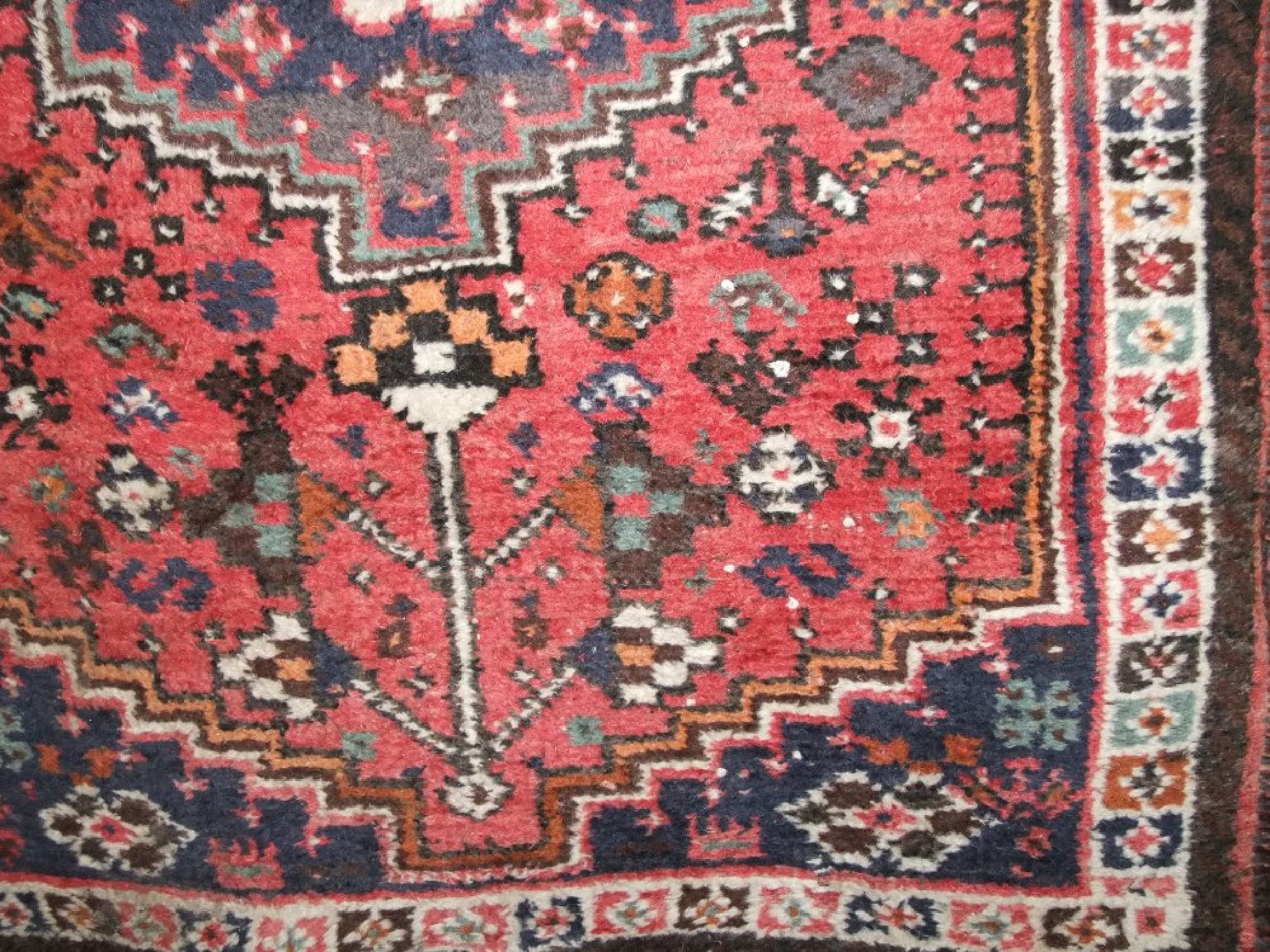 Appraisal: A coarse wool eastern rug with red field geometric and