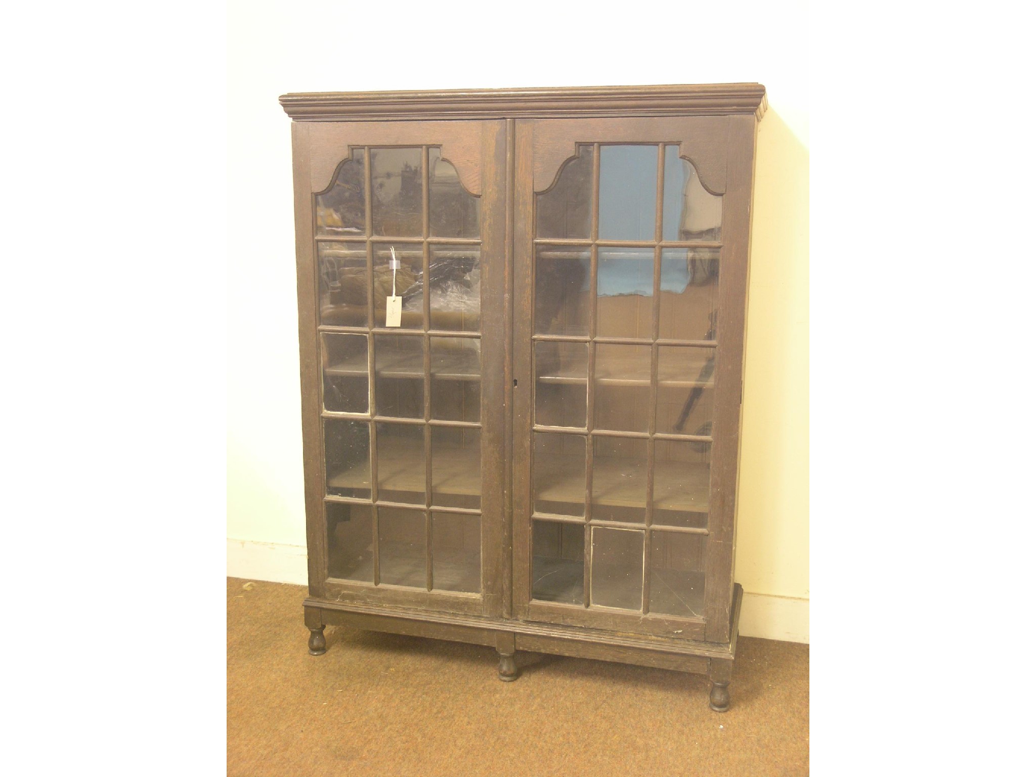 Appraisal: A solid dark oak bookcase three shelves enclosed by a