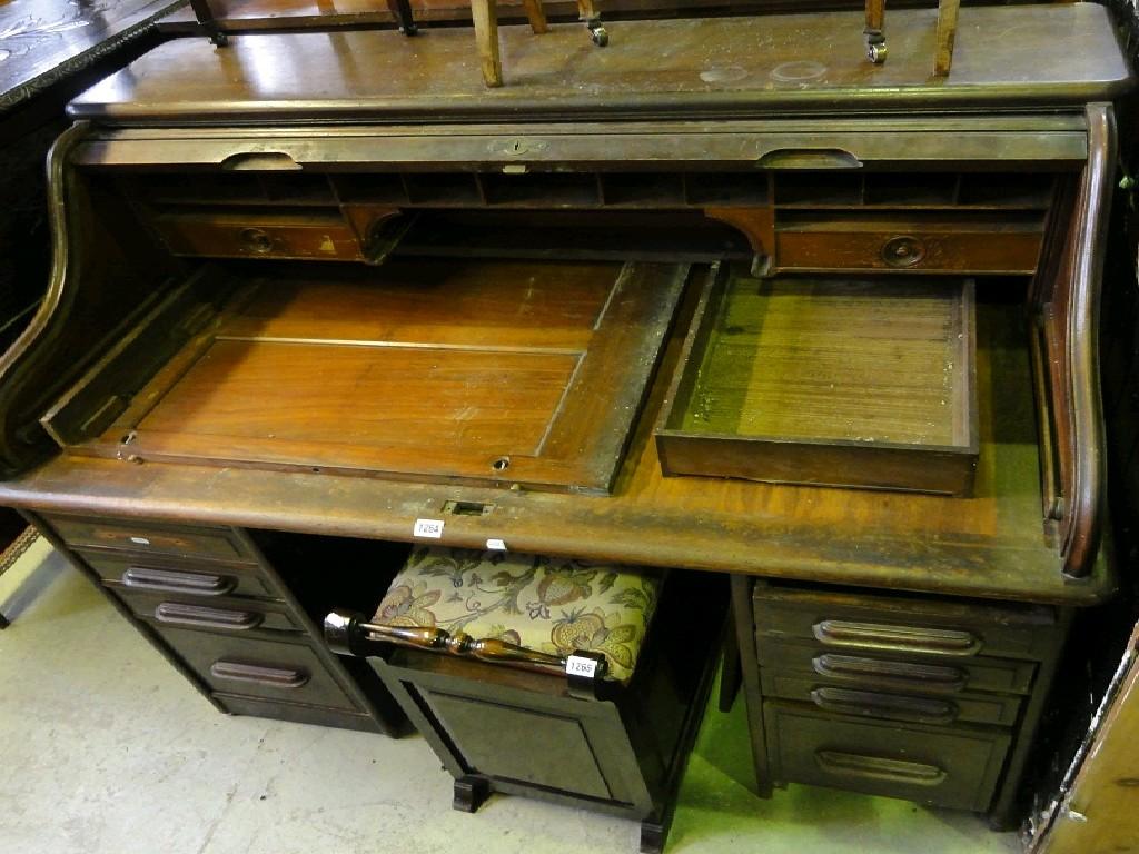 Appraisal: An Edwardian walnut roll top kneehole twin pedestal desk the