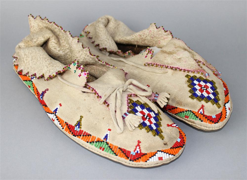 Appraisal: PAIR OF APACHE BEADED HIDE MOCCASINS WITH HIDE FRINGED SPLIT