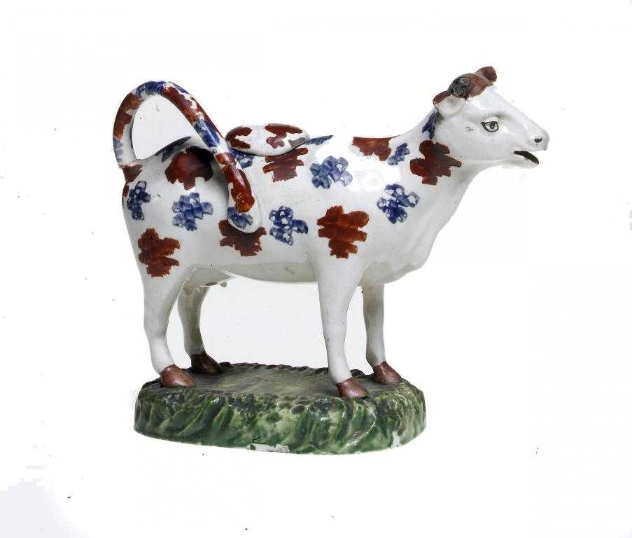 Appraisal: A STAFFORDSHIRE CREAMWARE COW CREAMER AND COVER sponged in red