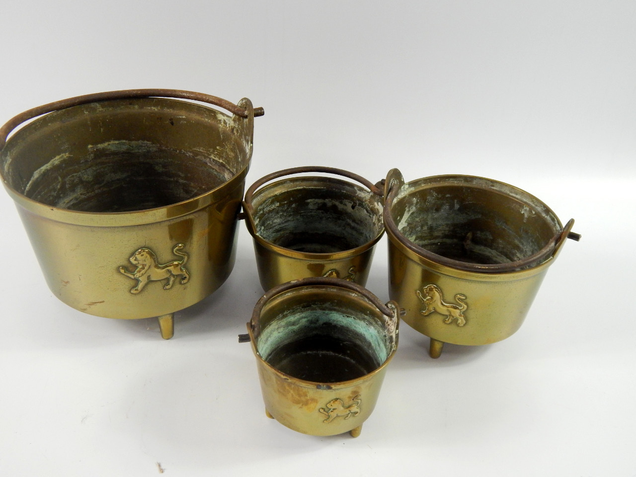 Appraisal: Four graduated brass cauldrons with iron handles embossed with a