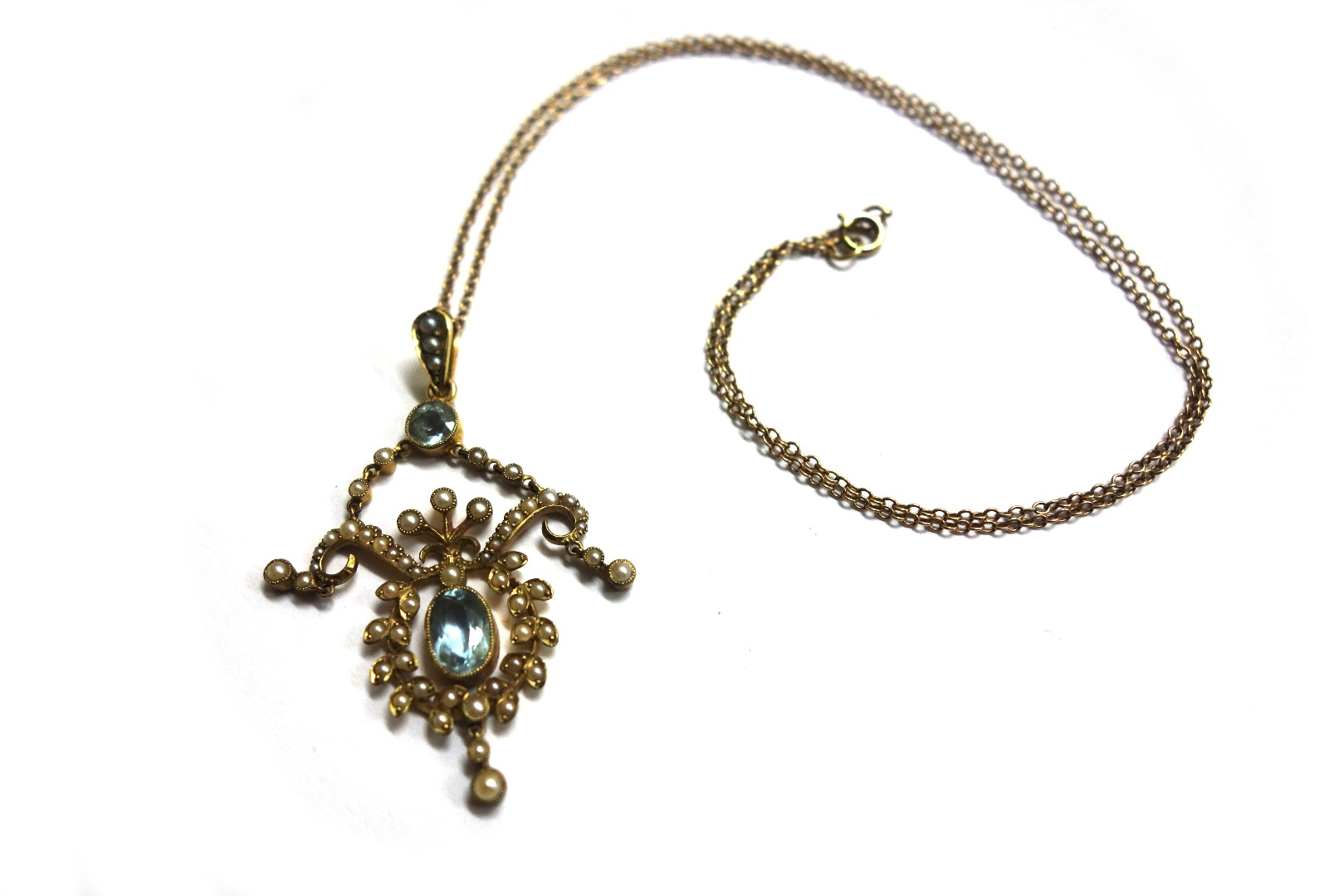 Appraisal: An Edwardian gold half pearl and aquamarine open pendant centred