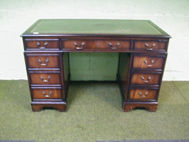 Appraisal: A reproduction mahogany kneehole desk with leather inset top