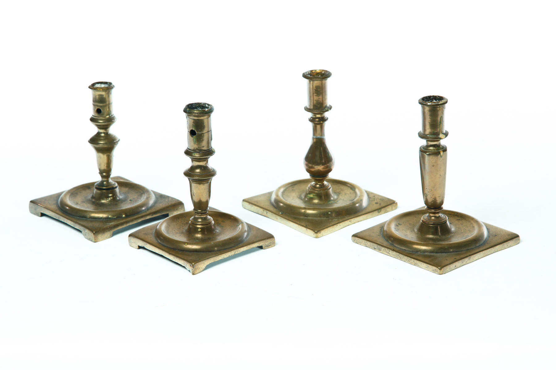 Appraisal: FOUR BRASS CANDLESTICKS European late th century Square bases with