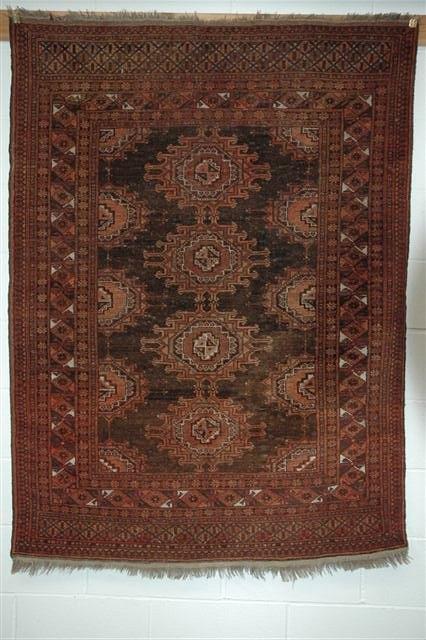 Appraisal: AN AFGHAN WINE GROUND RUG decorated a central multiple medallion