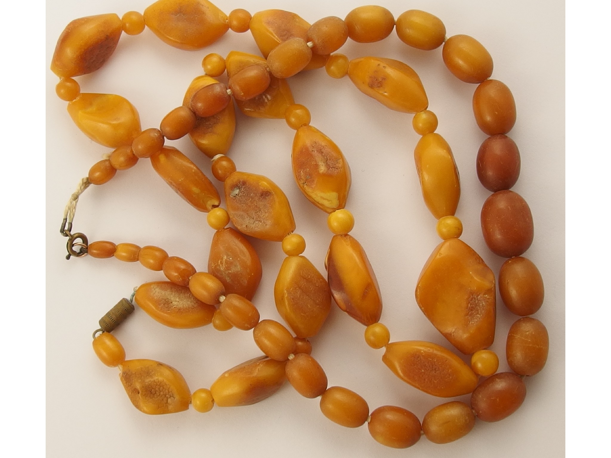 Appraisal: Two yellow butterscotch amber coloured bead necklacesthe larger of the