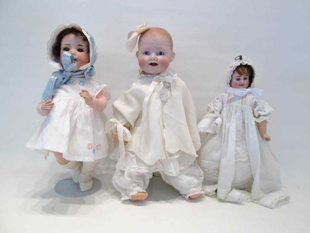 Appraisal: THREE BISQUE HEAD DOLLS the brunette with the blue ribbon