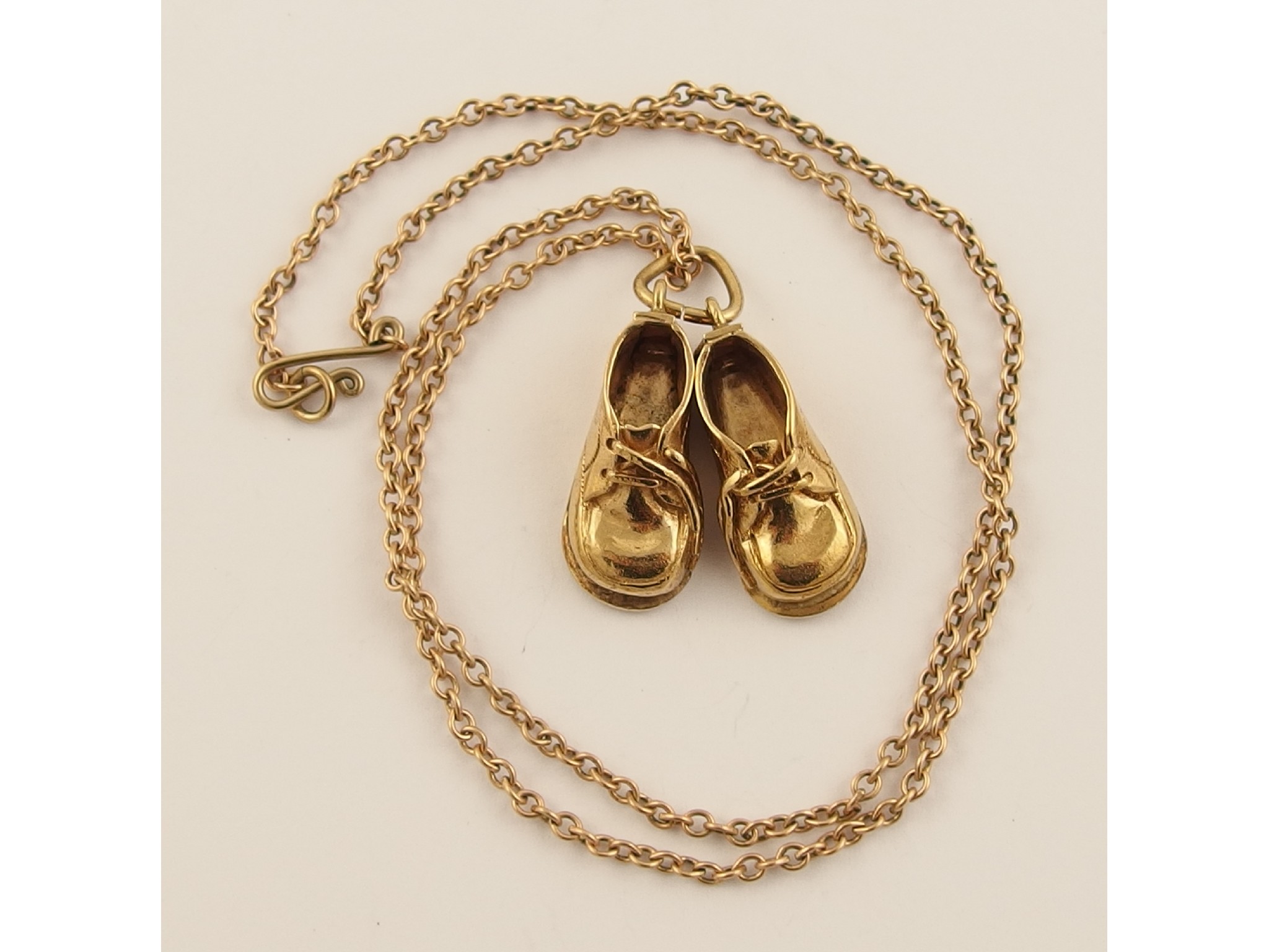 Appraisal: A ct pendant in the form of baby's shoes and