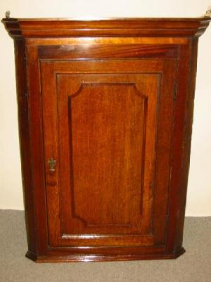 Appraisal: A GEORGE III OAK CORNER CUPBOARD the moulded cornice over