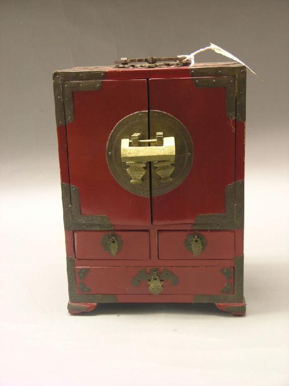 Appraisal: A Chinese table-top cabinet red lacquer with engraved brass mounts