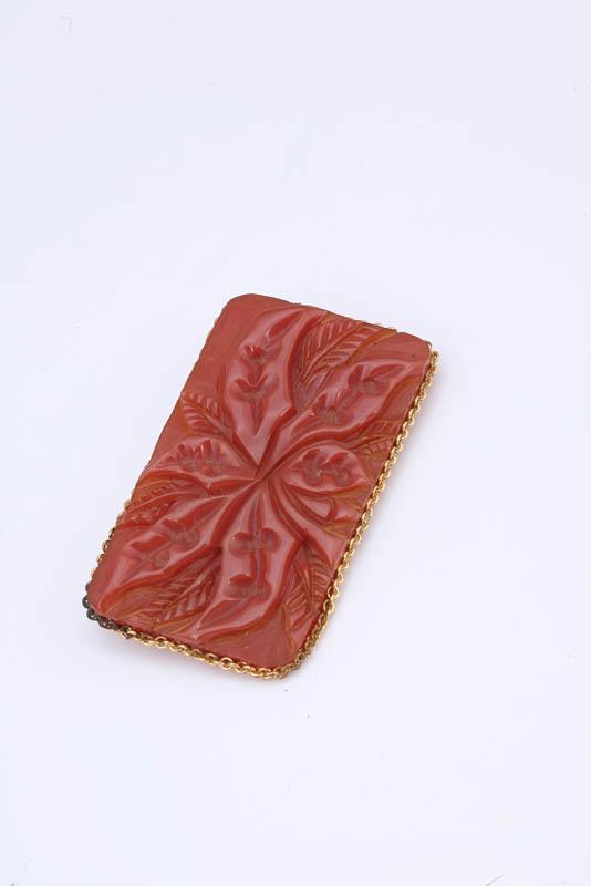 Appraisal: CARVED BAKELITE PIN Rectangular carnelian red pin with floral design