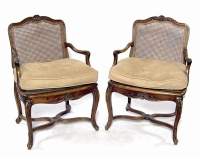 Appraisal: A pair of French carved walnut bergere open armchairs in