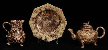 Appraisal: THREE ENGLISH ROCKINGHAM-GLAZED TEA ARTICLES Comprising a tripod pot and