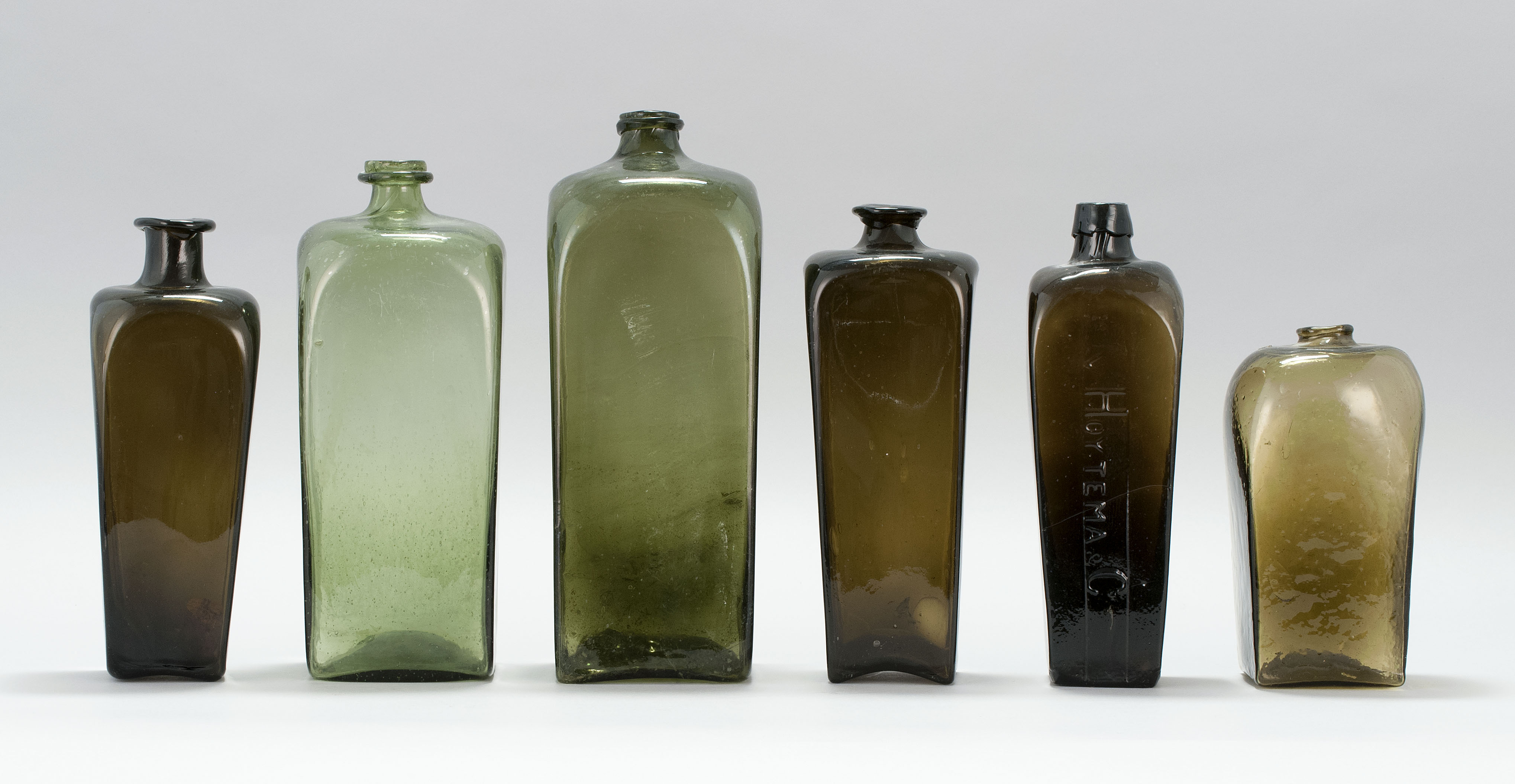 Appraisal: SIX EARLY BLOWN GLASS GIN BOTTLES th CenturyIn amber and