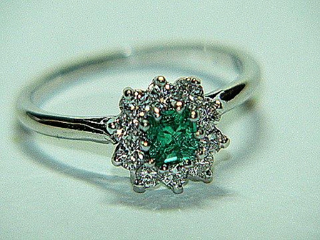 Appraisal: An Emerald and Diamond Cluster Ring claw-set with central square-cut