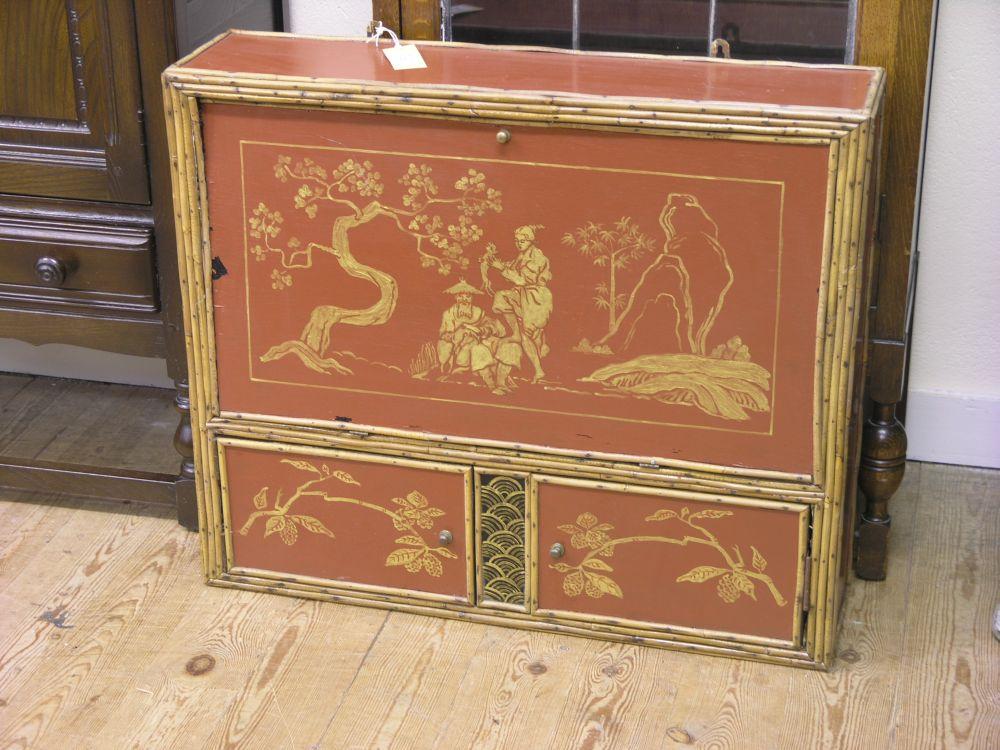 Appraisal: A bamboo and lacquer fall-front desk with two cupboards beneath