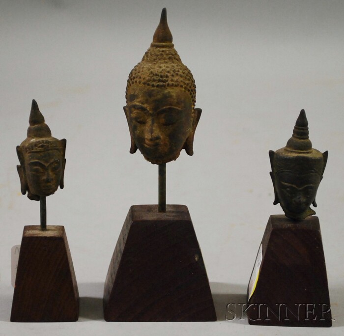 Appraisal: Three Small Bronze Buddha Heads mounted on wood bases ht