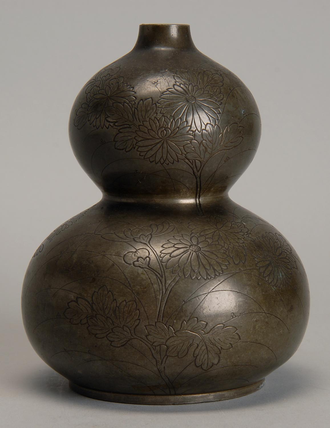 Appraisal: PEWTER-CASED SAKE BOTTLE Meiji PeriodIn double-gourd form with engraved chrysanthemum