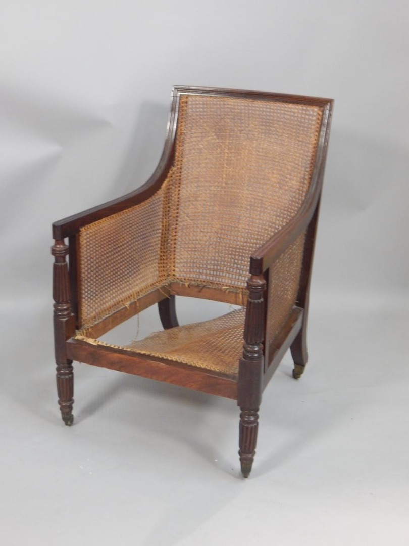 Appraisal: A George IV mahogany bergere armchair with a reeded frame