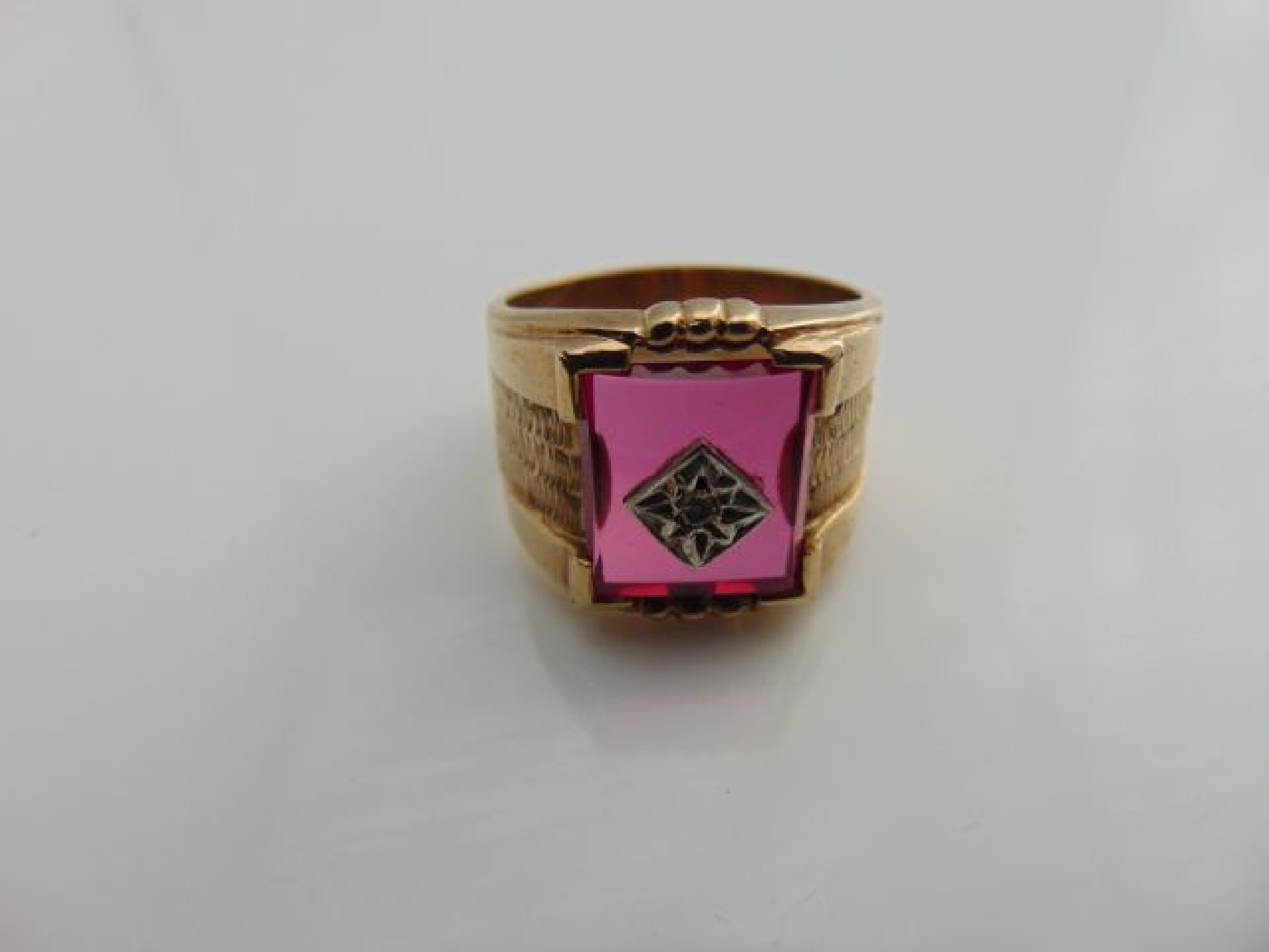 Appraisal: A gem-set ring centred with a rectangular pink plaque mounted