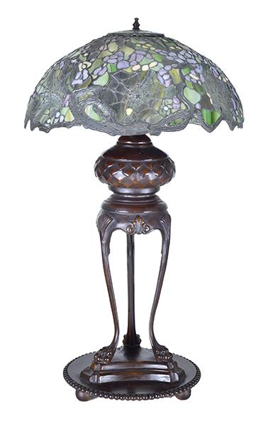 Appraisal: A TIFFANY STYLE LAMP on an openwork bronze tri lion