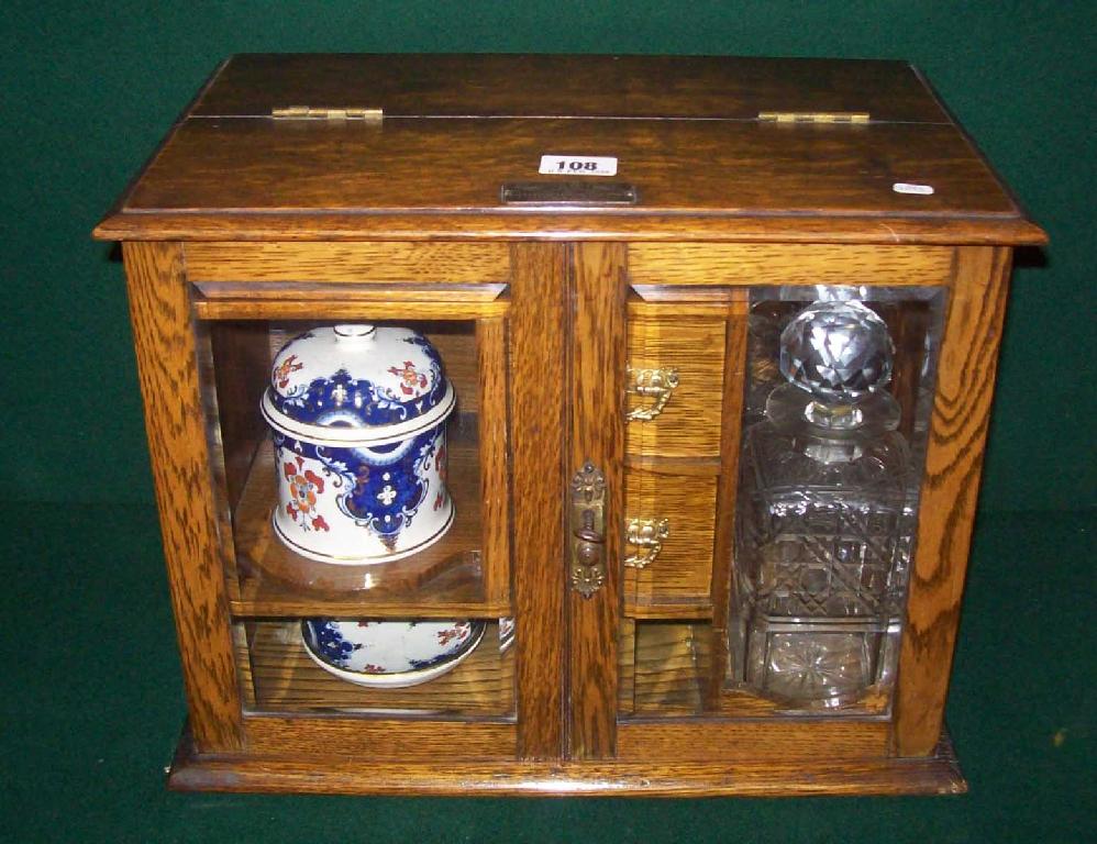 Appraisal: An oak cased smoking cabinet the interior fitted with a