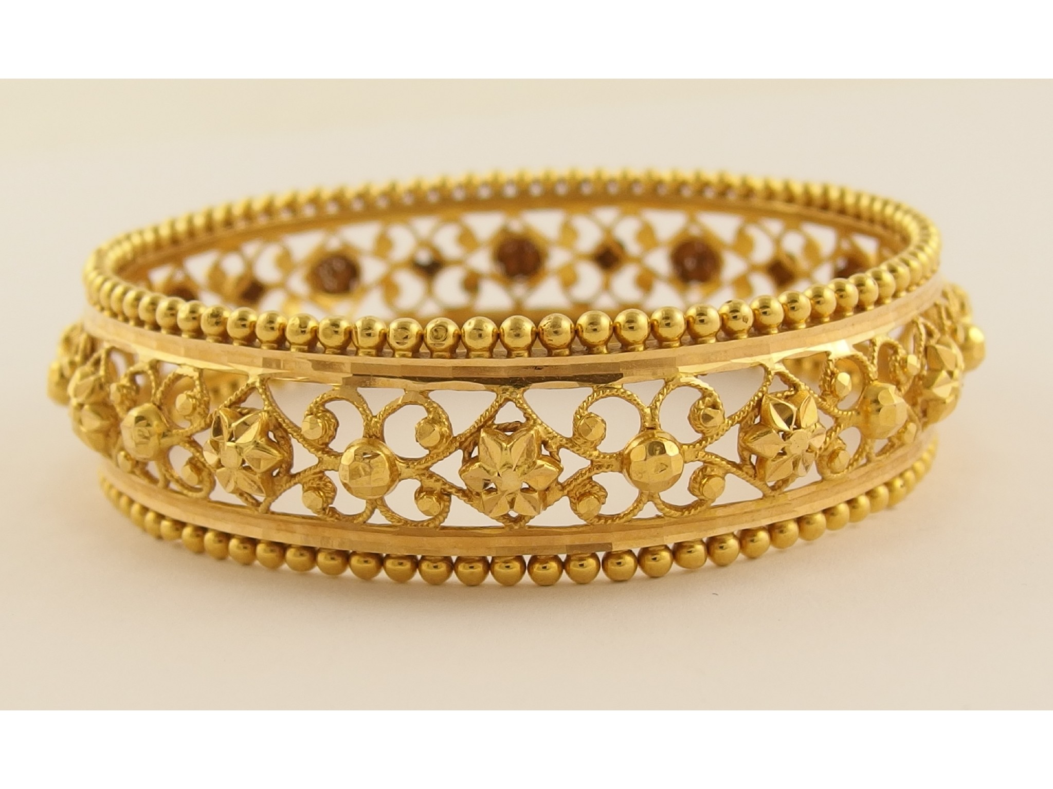 Appraisal: A filigree bangle stamped ctwith cut work floral decoration and