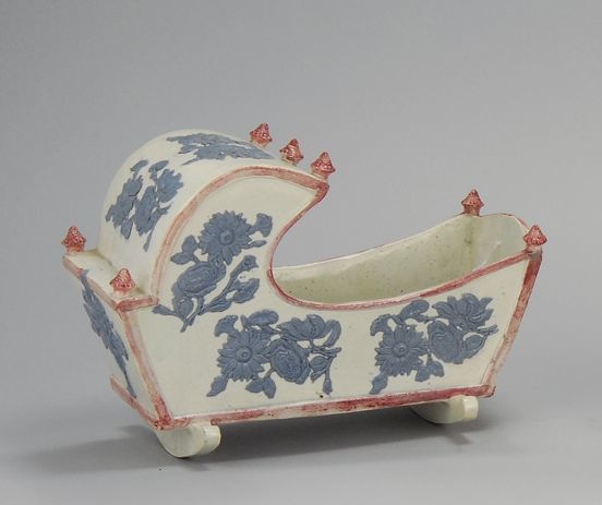 Appraisal: LARGE PEARLWARE CRADLE Circa With raised blue floral design and