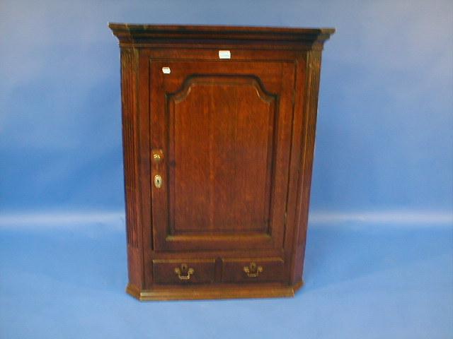 Appraisal: A George II oak hanging corner cupboard with fielded and