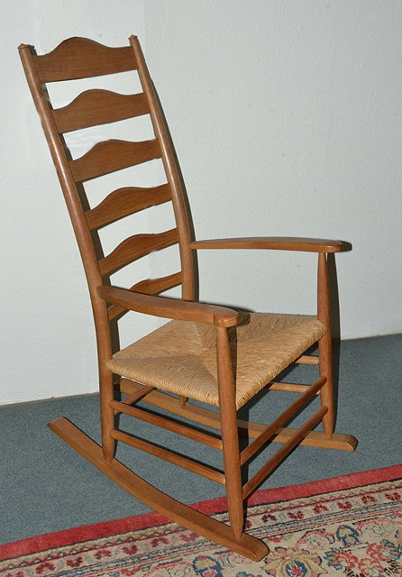 Appraisal: A COTSWOLD SCHOOL ASH LADDERBACK ROCKING CHAIR with rush seat