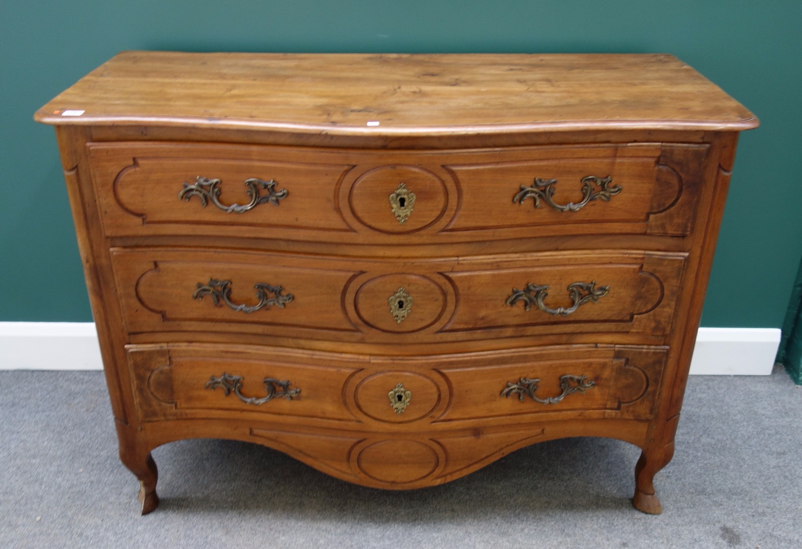 Appraisal: An th century French fruitwood commode with three serpentine long