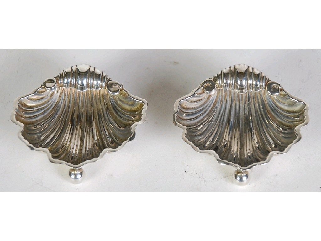 Appraisal: PAIR OF EDWARDIAN SILVER SHELL PATTERN SALTS raised on three