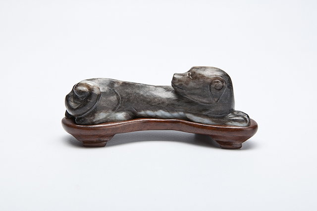 Appraisal: A CHINESE BLACK AND WHITE JADE RECUMBENT HOUND with wood