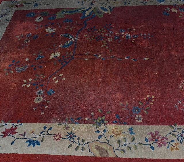 Appraisal: A Chinese red ground carpetcirca having a bird resting on