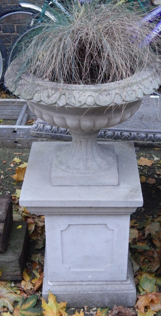 Appraisal: A stone semi fluted garden urn on a square plinth