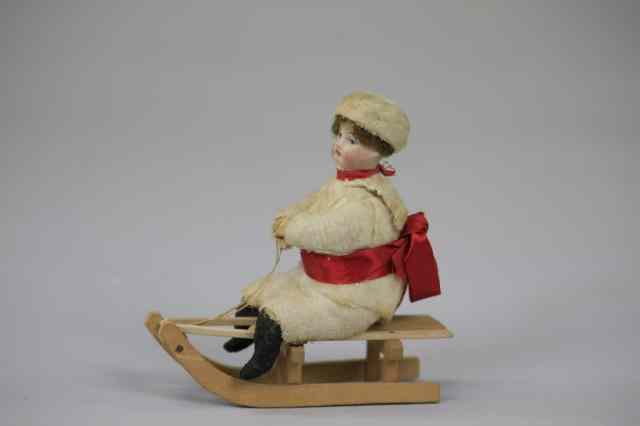 Appraisal: BISQUE HEAD CHILD ON SLED Germany Heubach spun cotton body