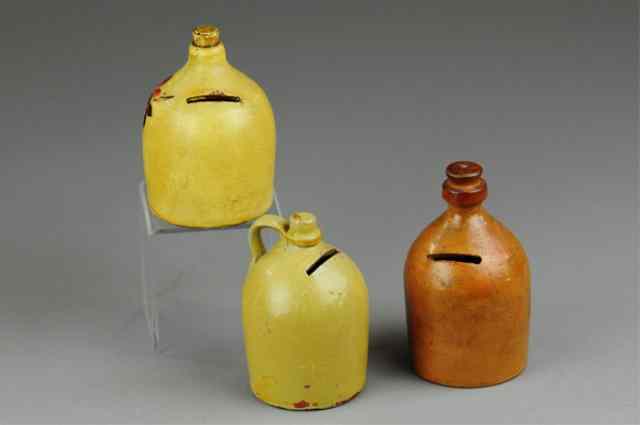 Appraisal: THREE POTTERY JUG STILL BANKS Includes two extensive floral decorations