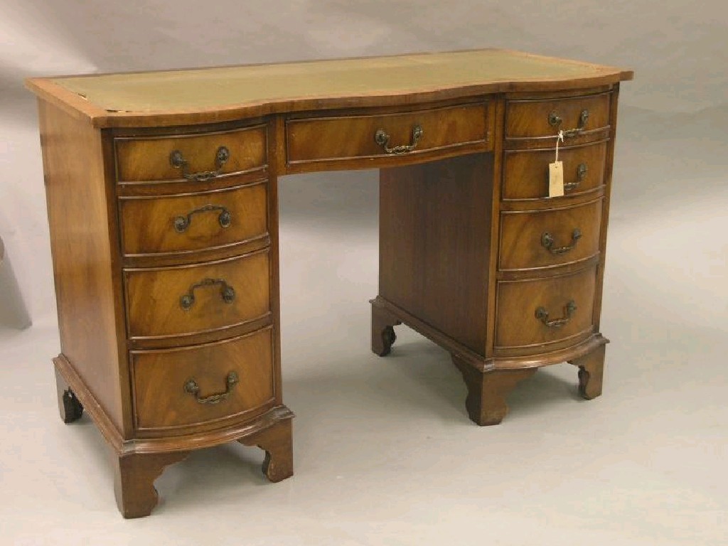 Appraisal: A reproduction mahogany desk serpentine fronted with inset leather top